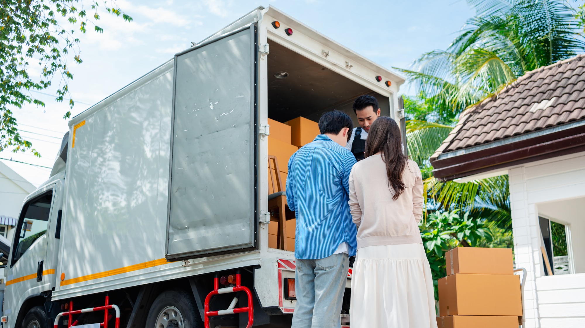 Asian Couple check while unloading boxes and furniture from a pickup truck