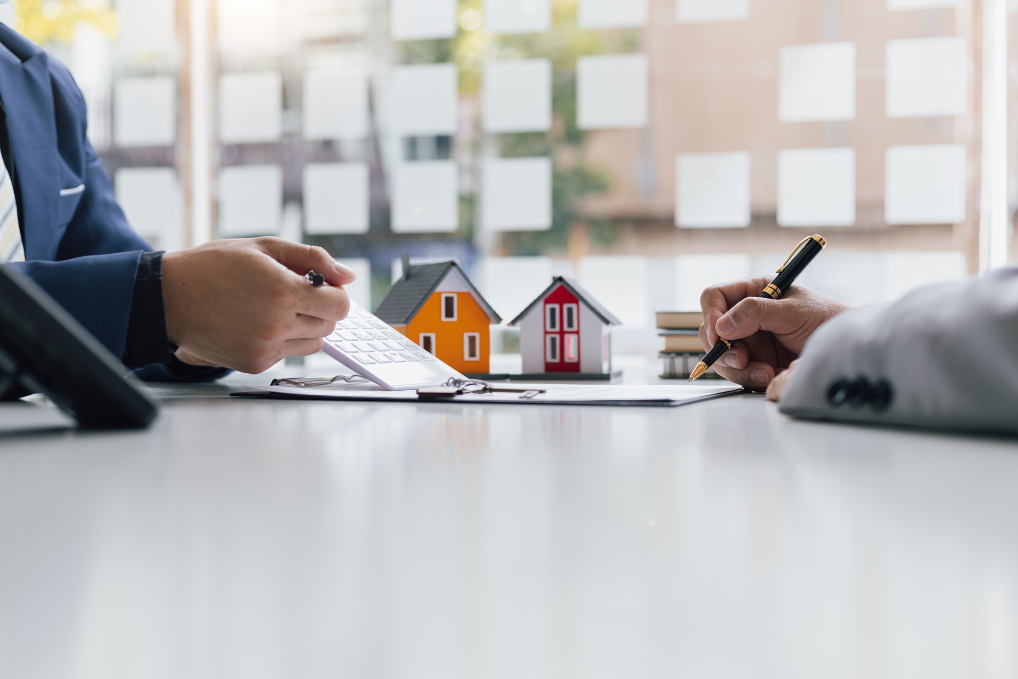 Businessmen and real estate agents sign contracts to legally sell homes.