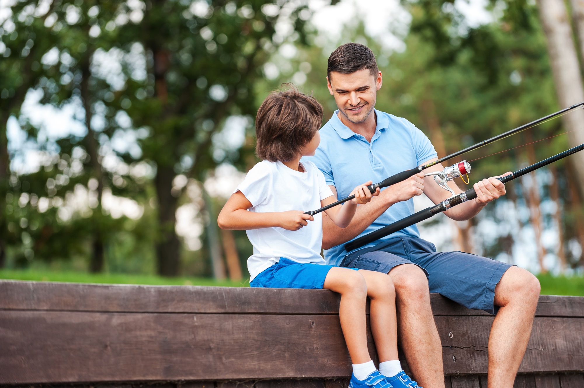 I t is all about right angle. Cheerful father and son fishing while sitting on quayside
