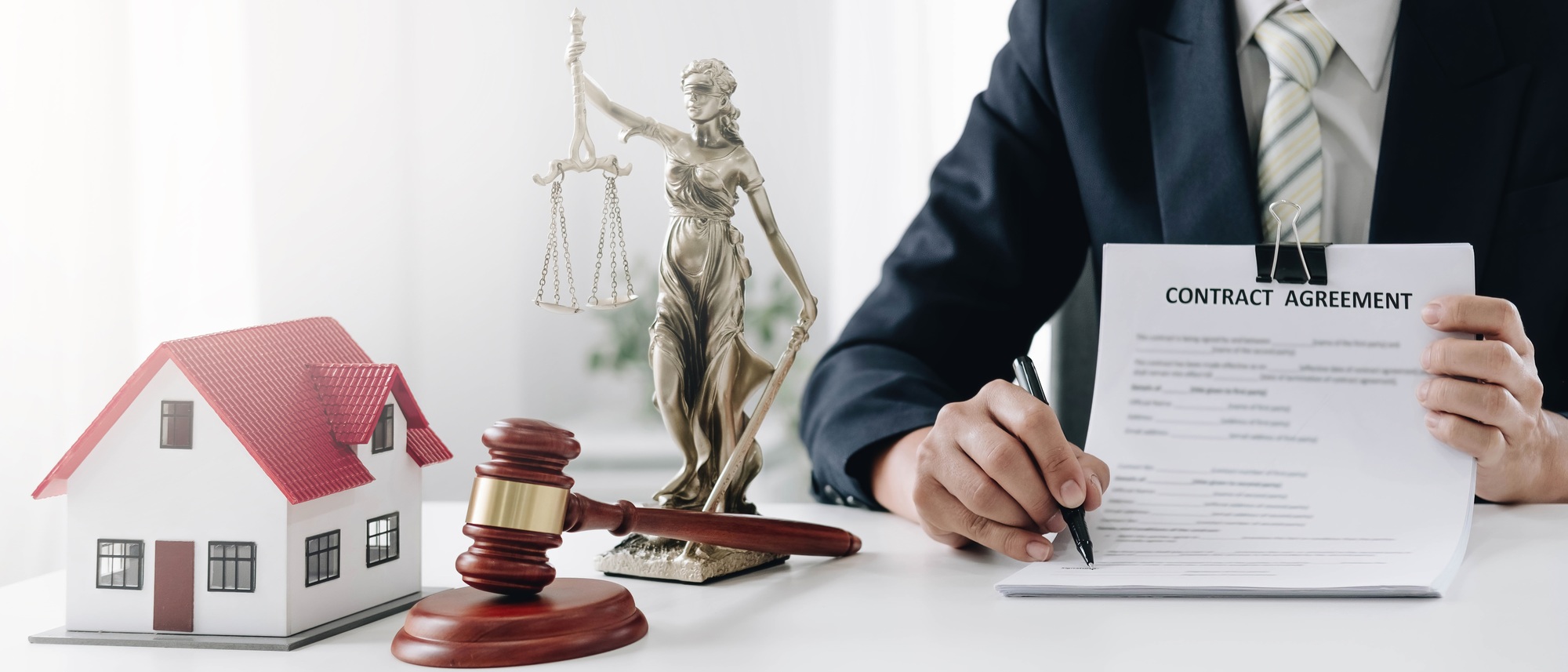 Judge gavel and house model on the table. Man signing in document. Real Estate Lawyer