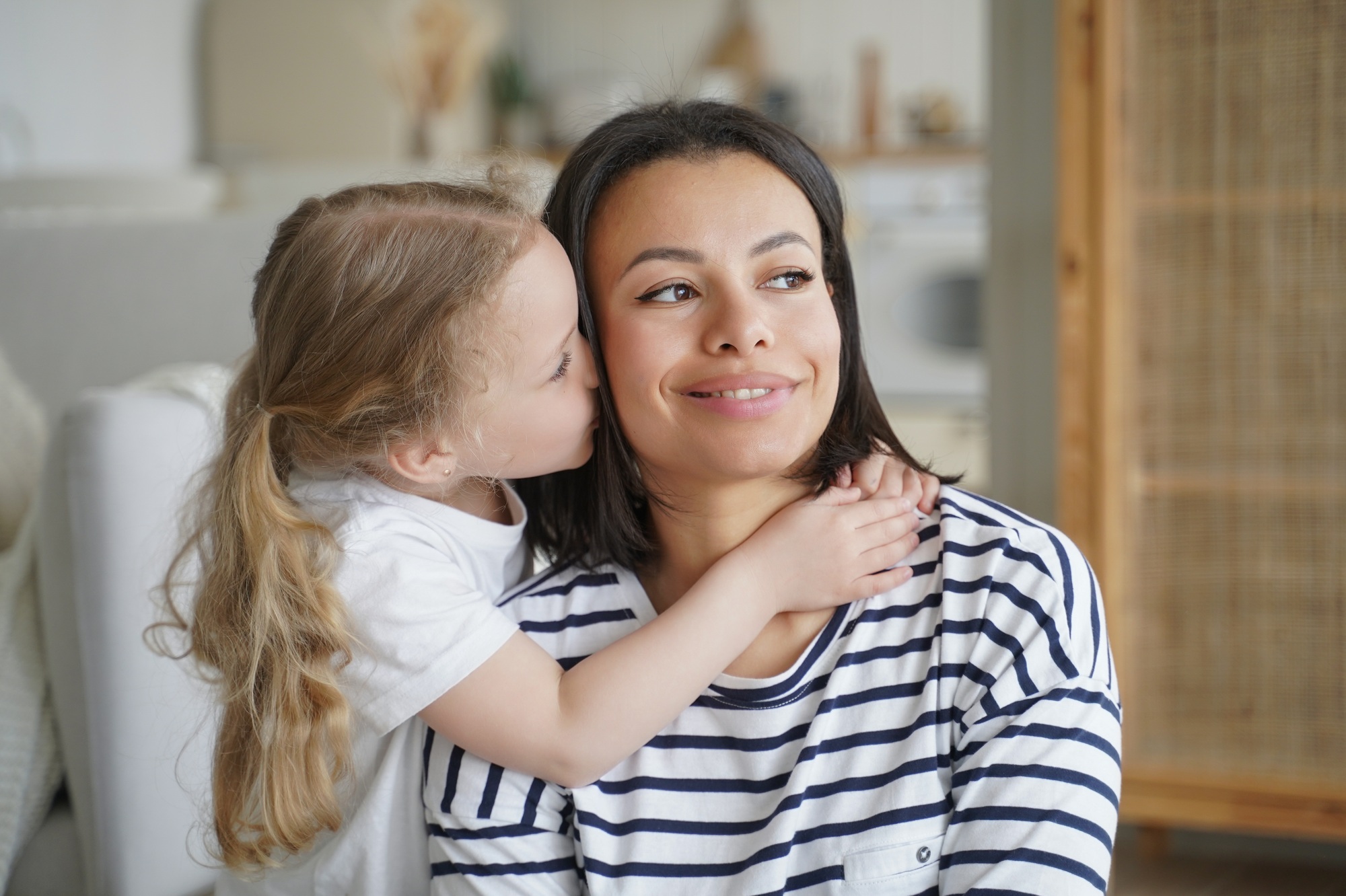 Loving adopted daughter hugs, kissing foster mom. Happy motherhood, custody of child girl, adoption