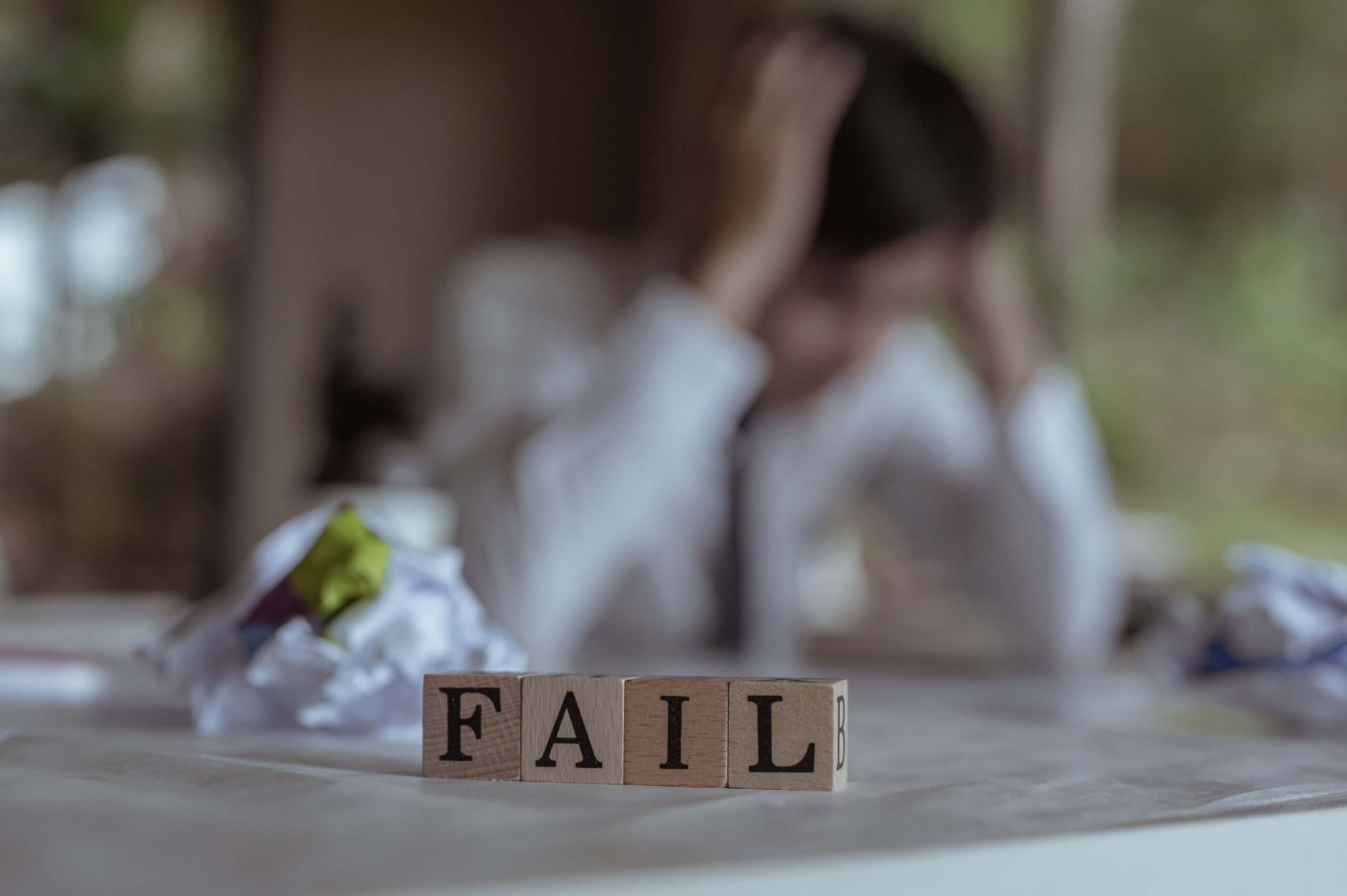 troubled person with fail blocks and crumpled paper
