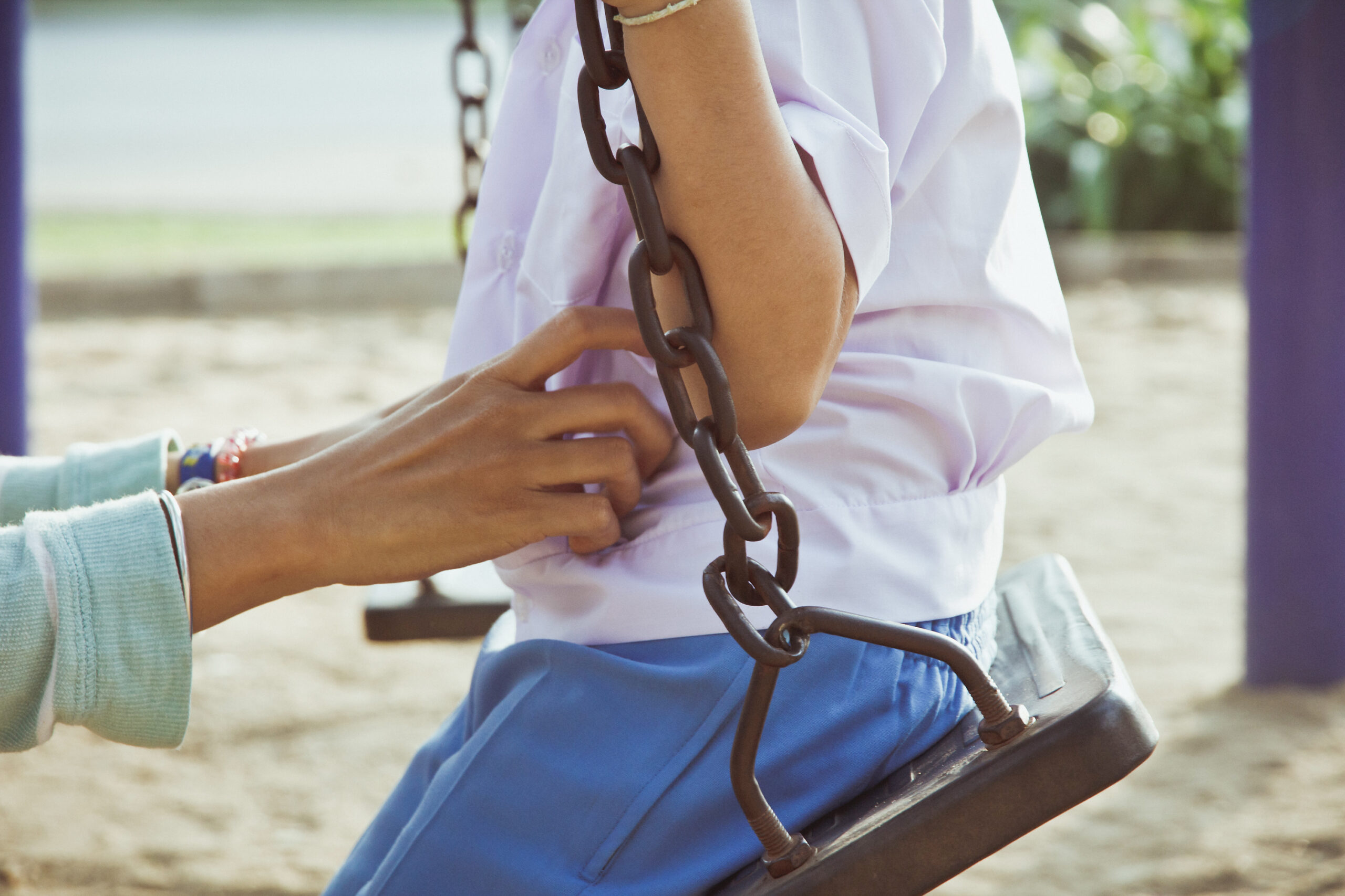 child on swing assisted by adult hand